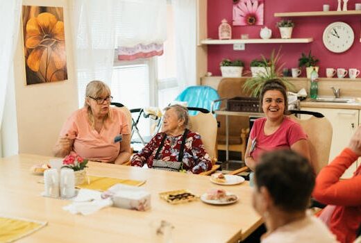 Elderly residents and caregivers enjoying a meal and conversation in a cheerful dining space.